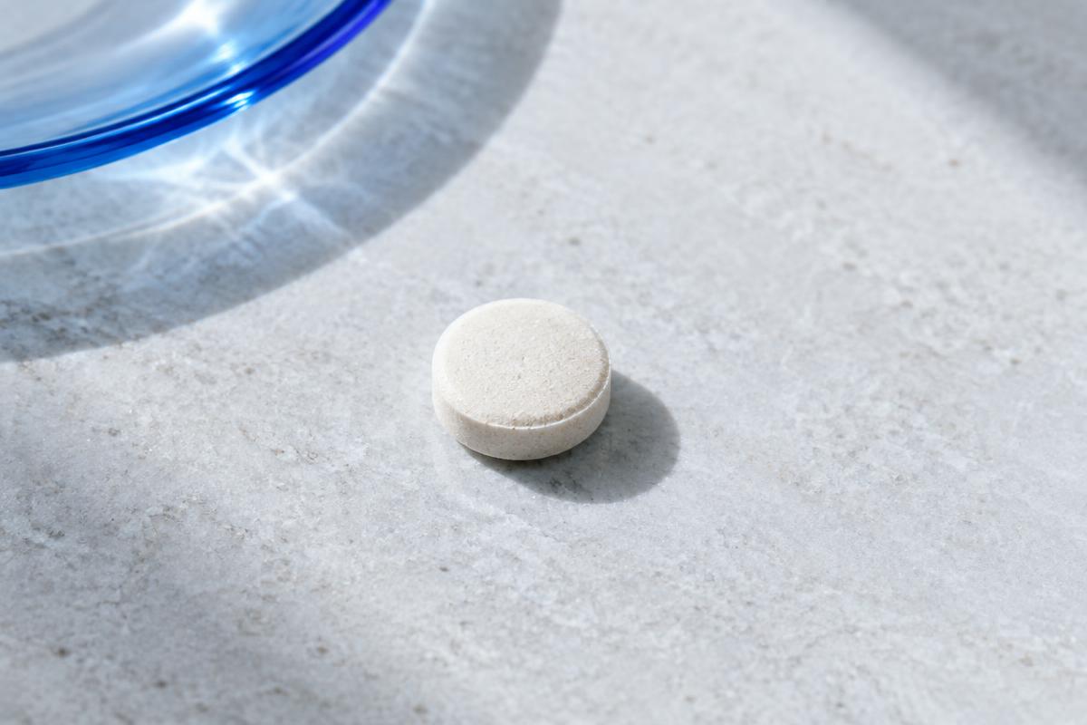A small chewable tablet on a pale stone surface